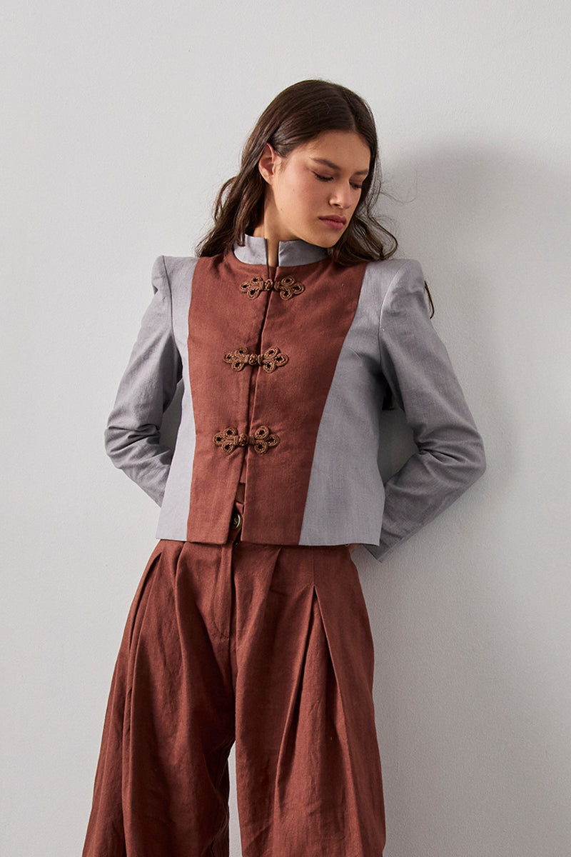 Chaqueta bicolor con cuello mao y hombreras en color gris. Detalle de chaleco a contraste en color marrón.