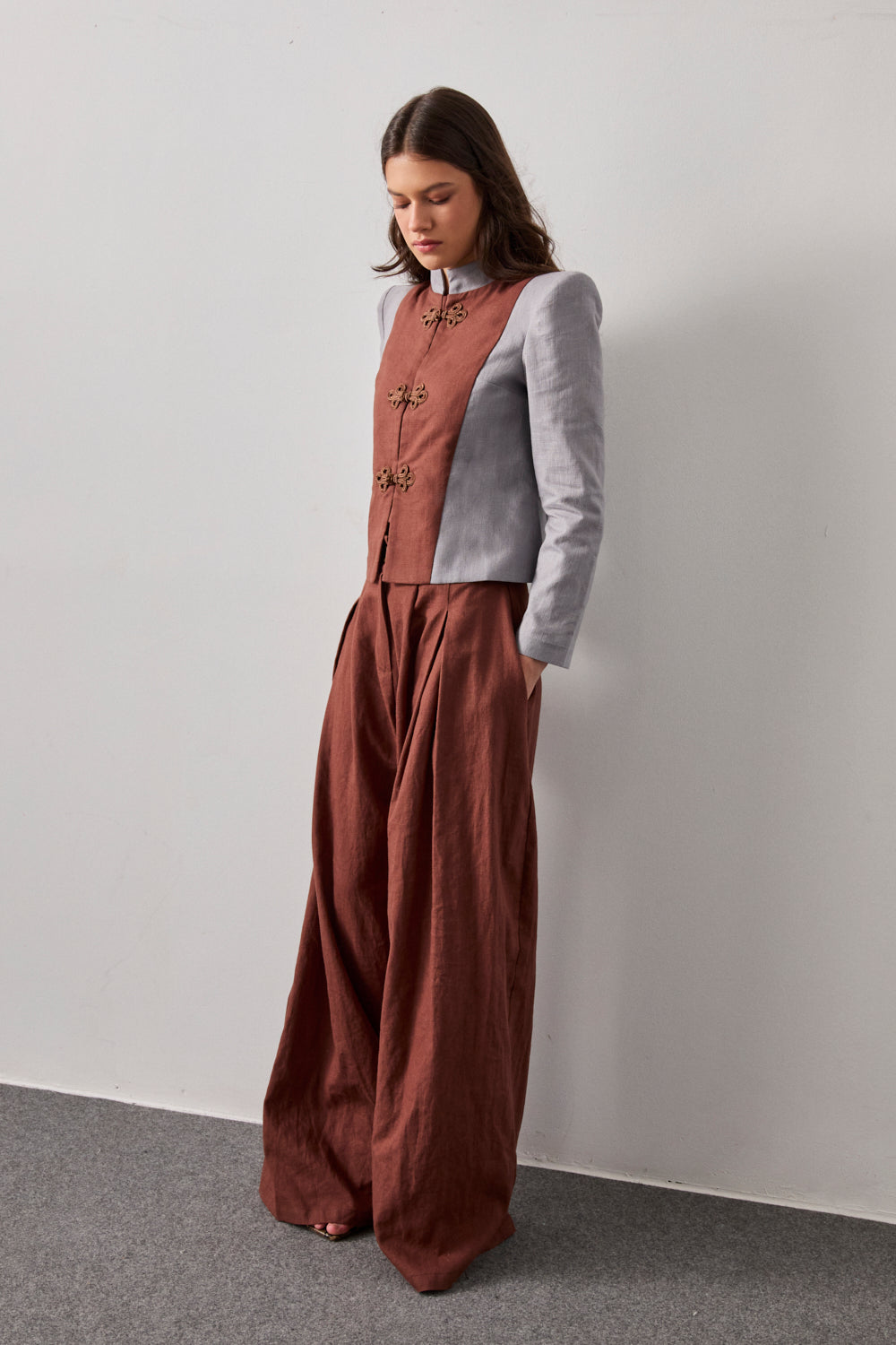 Chaqueta bicolor con cuello mao y hombreras en color gris. Detalle de chaleco a contraste en color marrón.