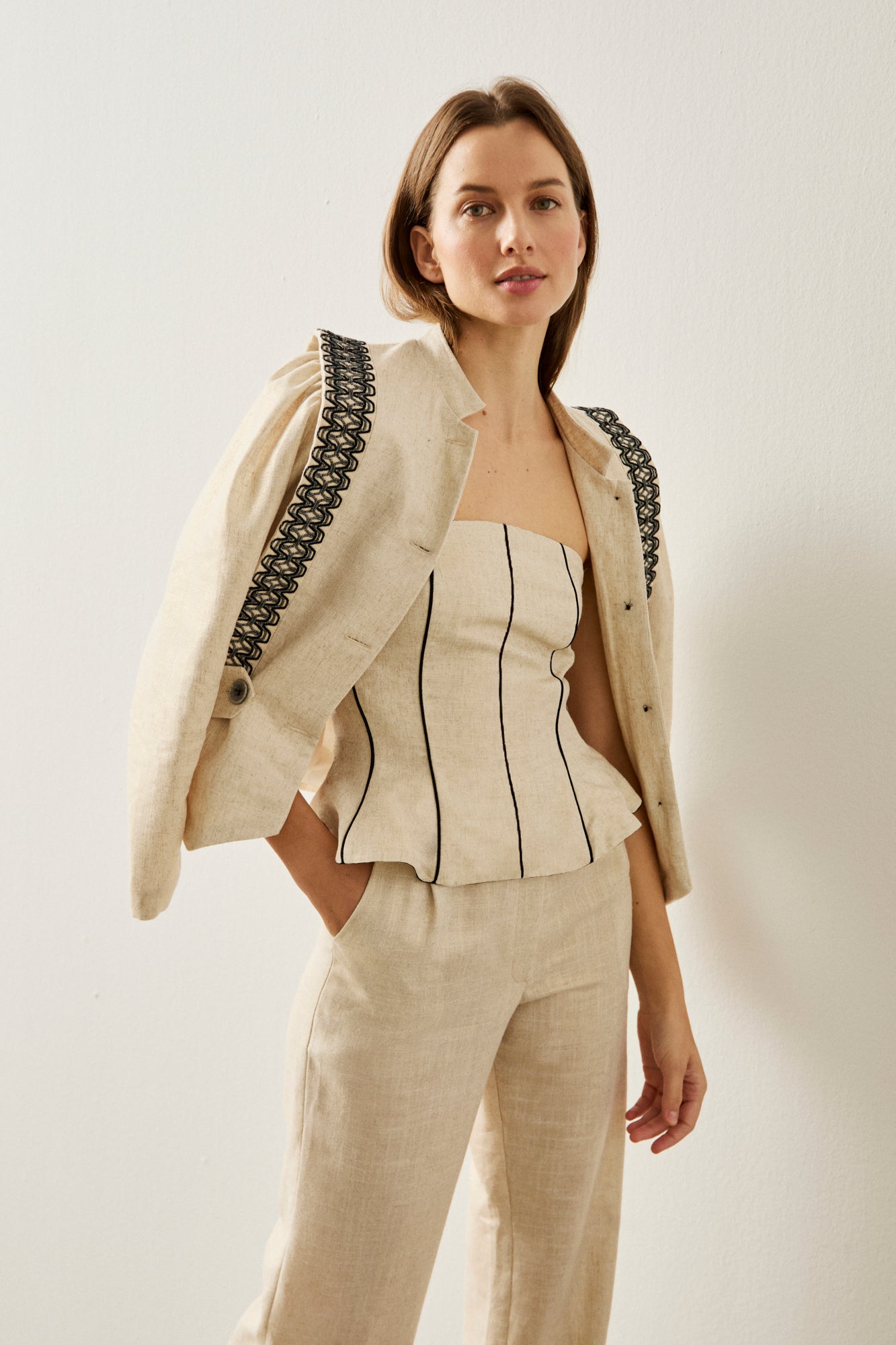 Pantalón de pinzas y pernera recta en color crema con ligero brillo.