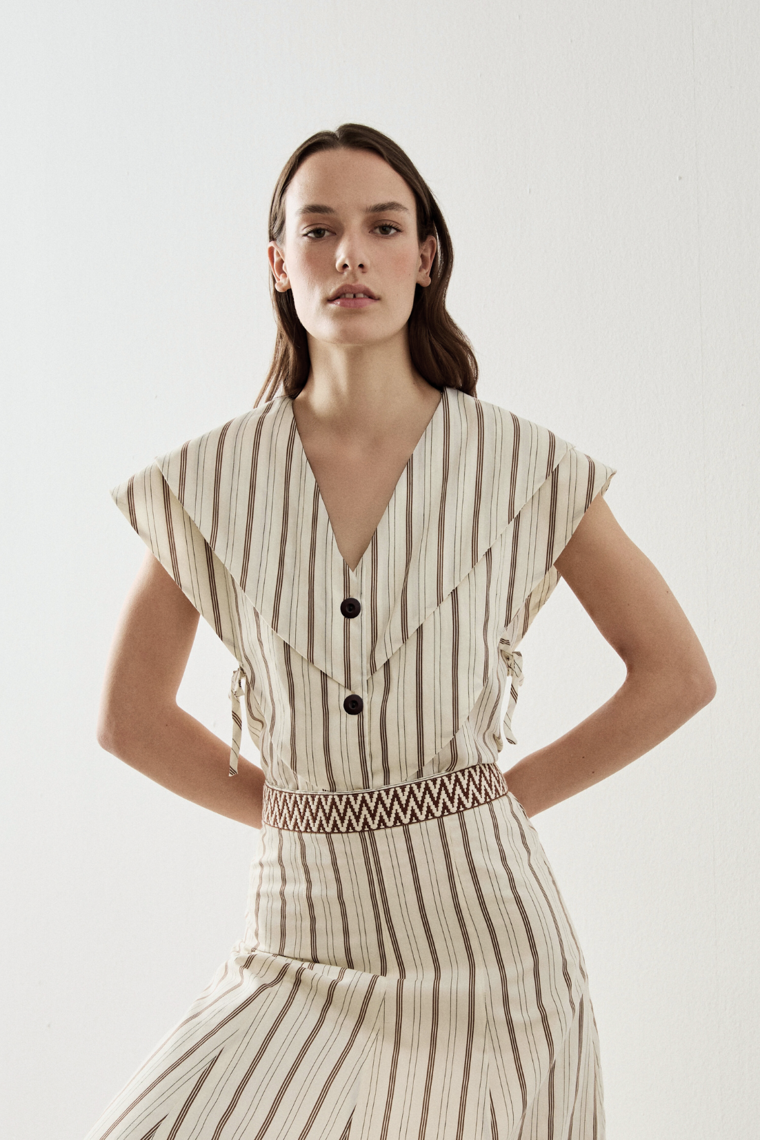 Top de manga corta en color crudo con rayas y escote en uve. Este top cuenta con capas superpuestas y tiene detalle con lazada en el lateral.