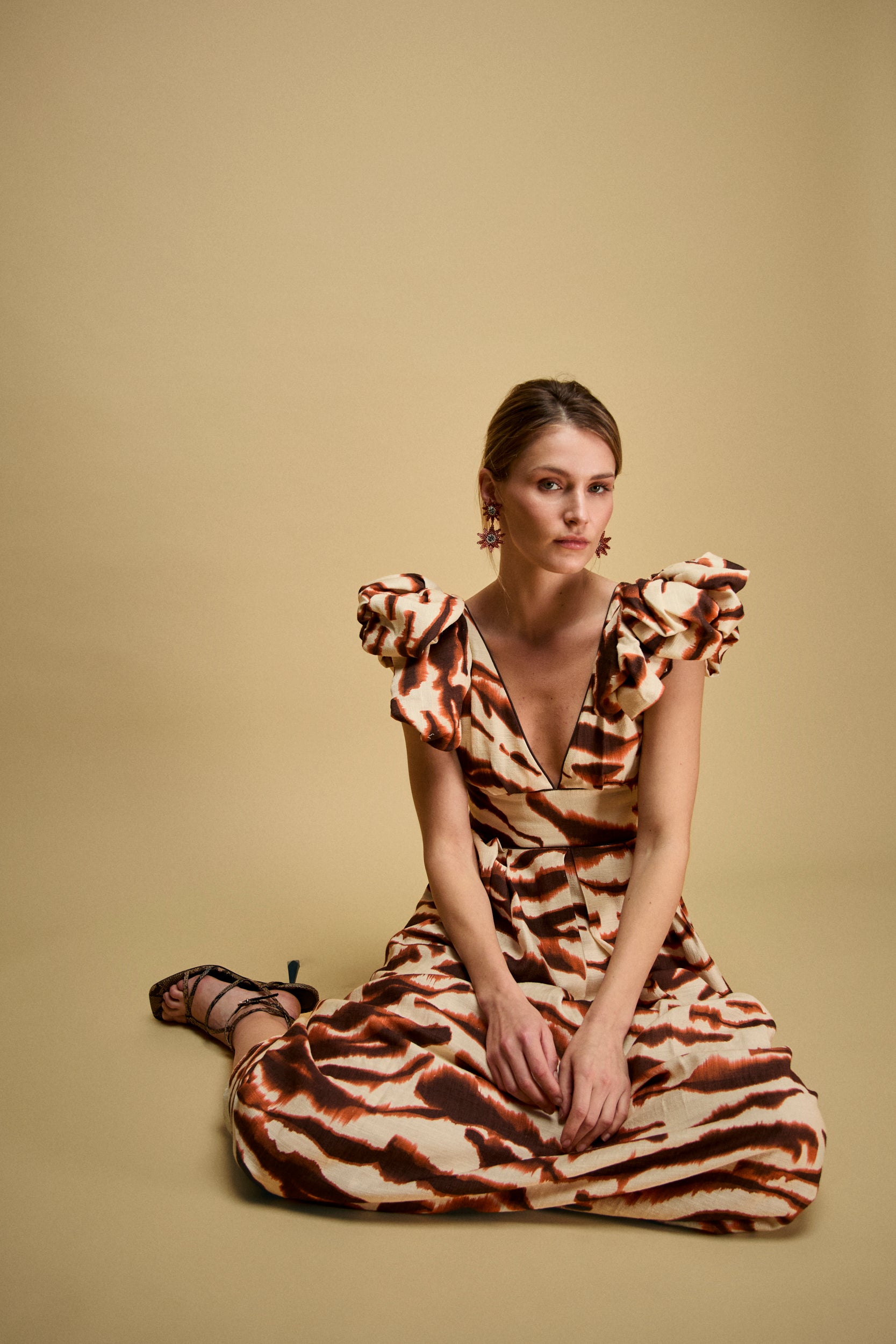 Vestido midi estampado en tonos marrones y teja con escote en V y lazadas en hombros.