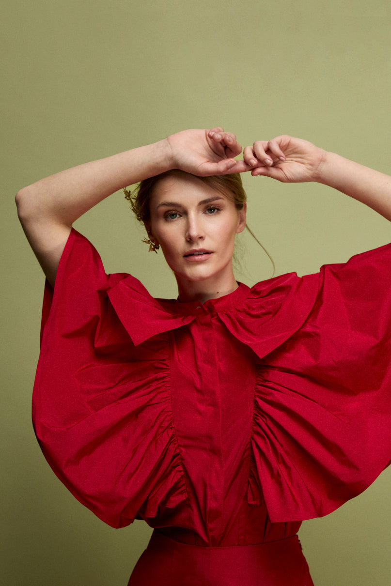 Blusa confeccionada en tafeta en color carmín con frunces y volantes en mangas.