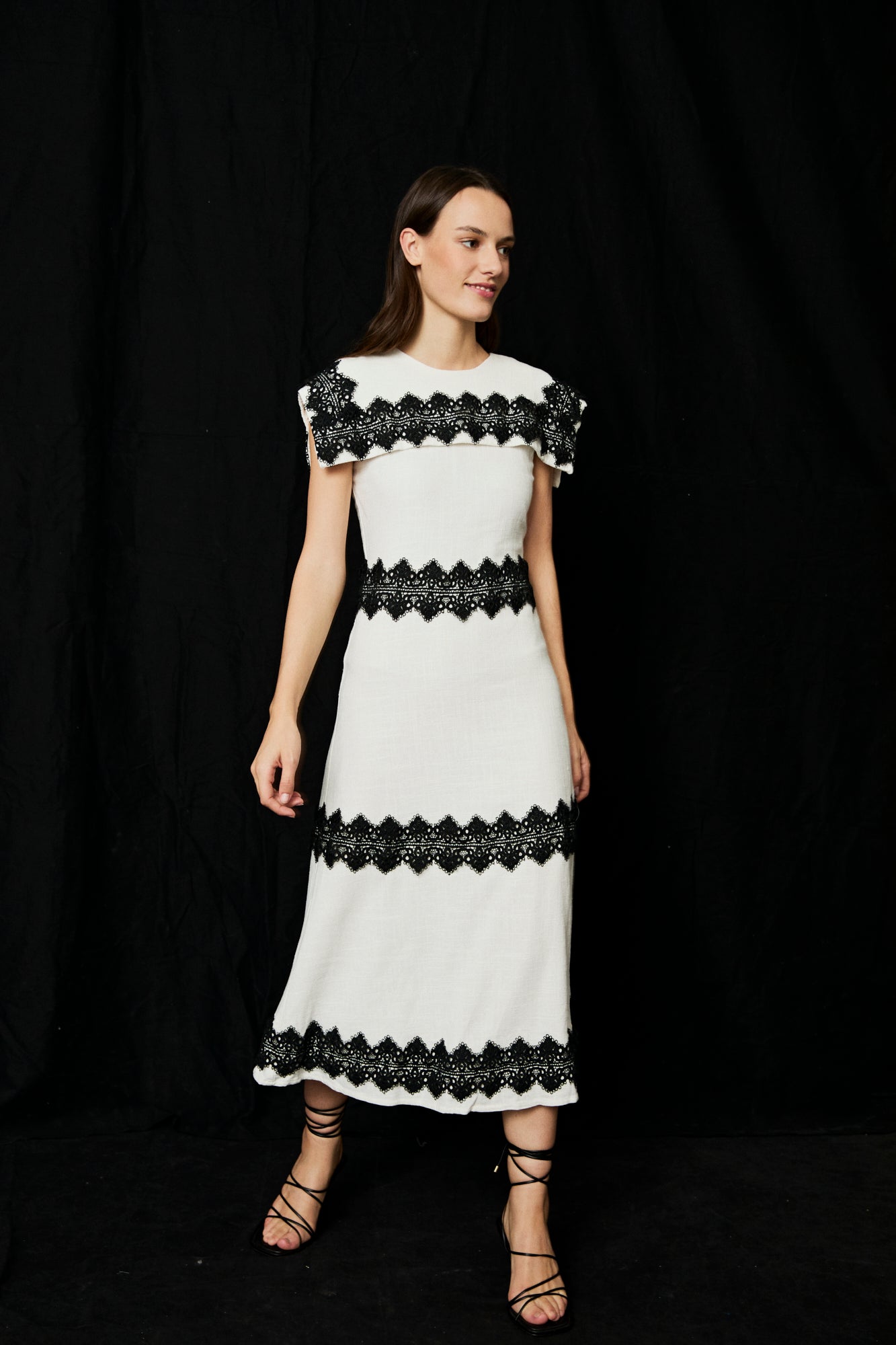 Vestido midi en color blanco con detalles de pasamaneria en negro.