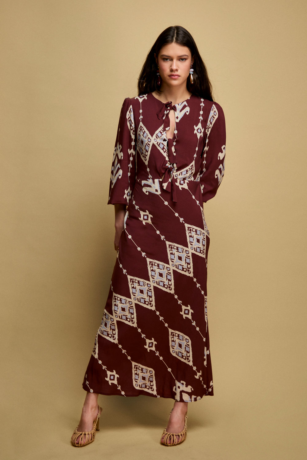 Vestido midi en color burdeos con escote a la caja y manga larga.Este vestido tiene corte en la cintura con lazadas en la parte frontal y falda con corte evasé.